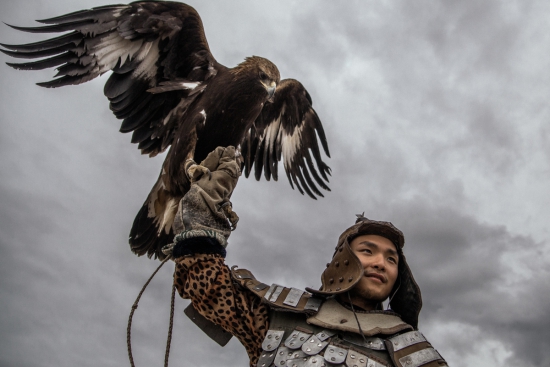Молодой человек из Улан-Батора позирует с соколом, используемым для охоты. Это привлекает дополнительный доход от туристов.